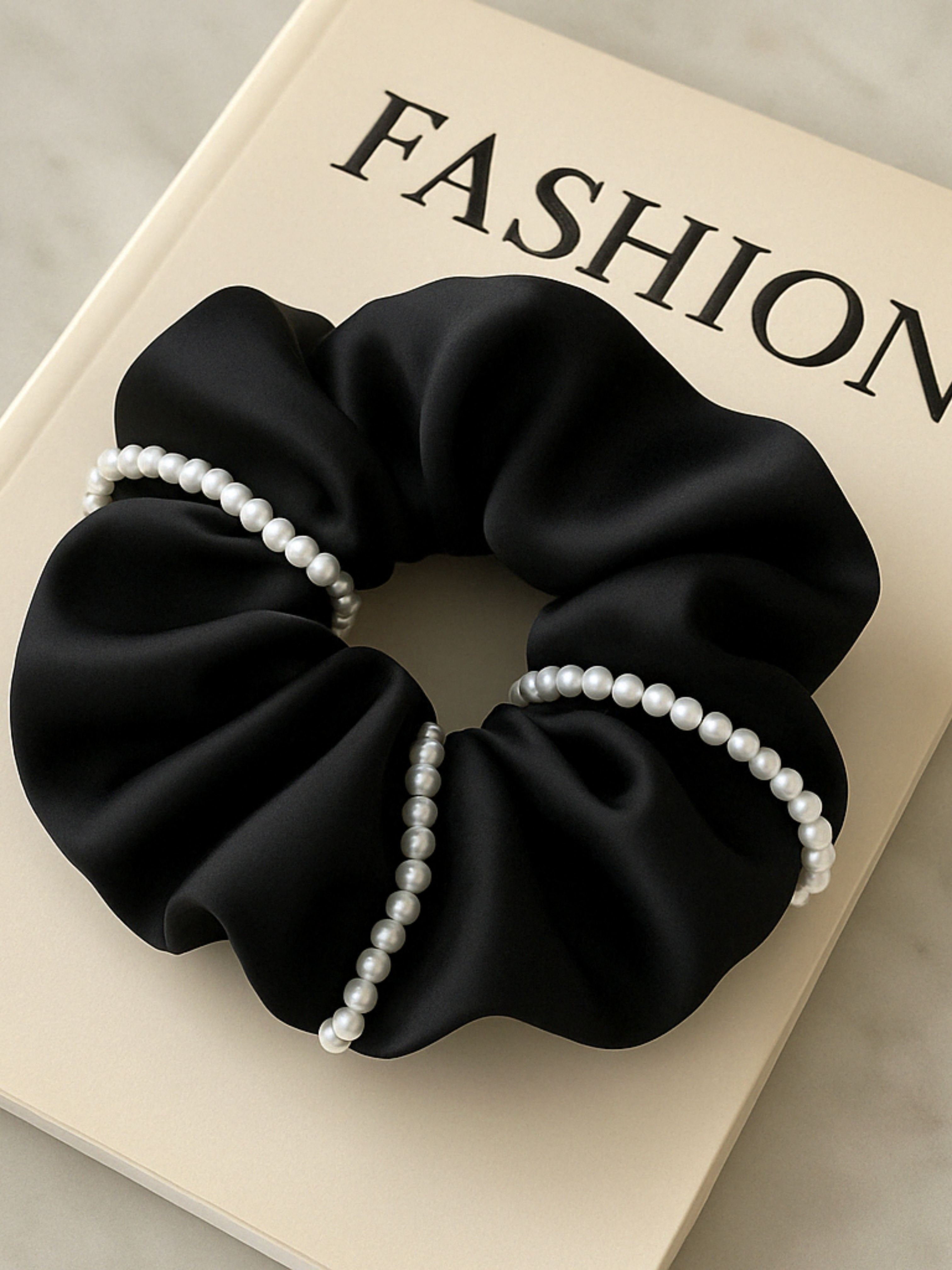 Chouchou noir en satin décoré de perles blanches, accessoire cheveux chic pour femme élégante.