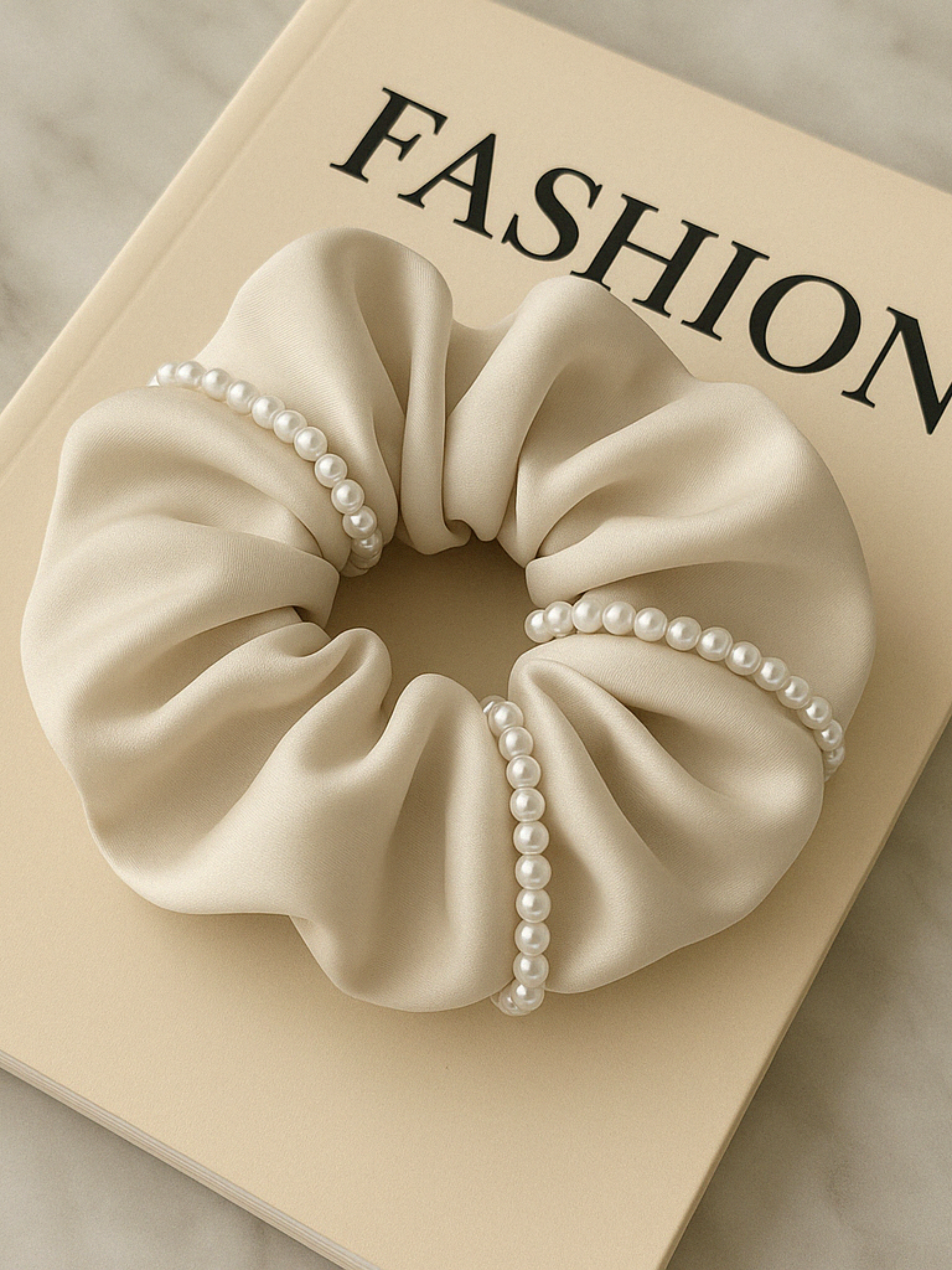 Chouchou crème en satin orné de perles blanches, idéal pour une coiffure élégante et tendance.